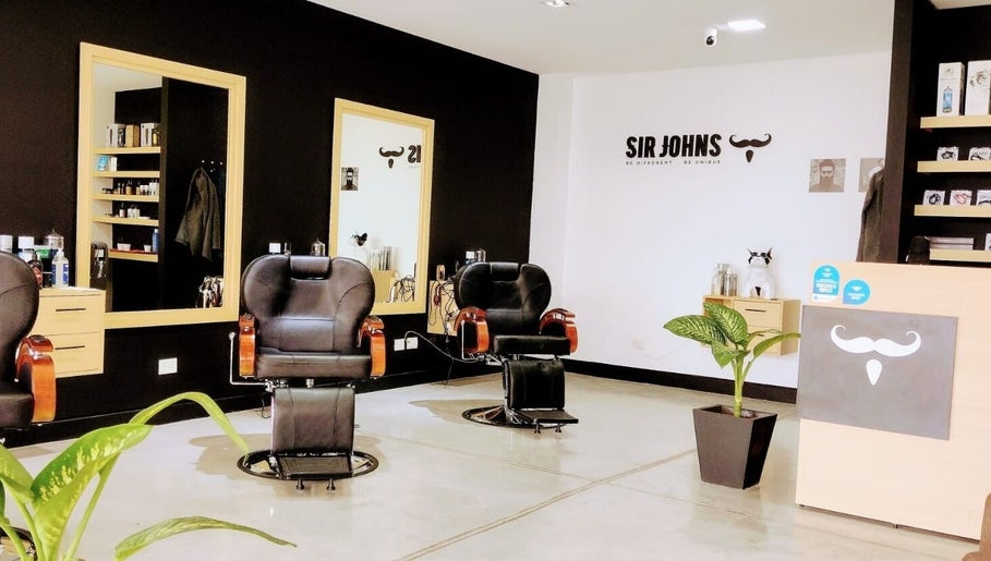 Interior moderno de Sir Johns El Punto Shopping en San Lorenzo Chico, Salta, AR, con sillas de peluquería y decoración elegante.