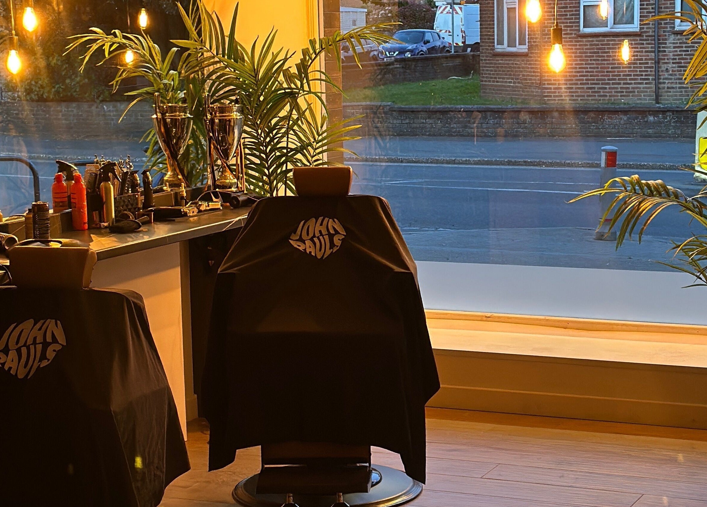 Interior of John Pauls Barbershop in Lancing, England, with stylish chairs and warm lighting.