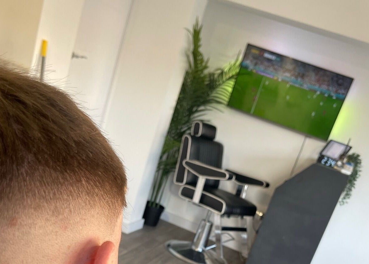Modern barber chair and TV at John Pauls Barbershop, Lancing, England, GB.
