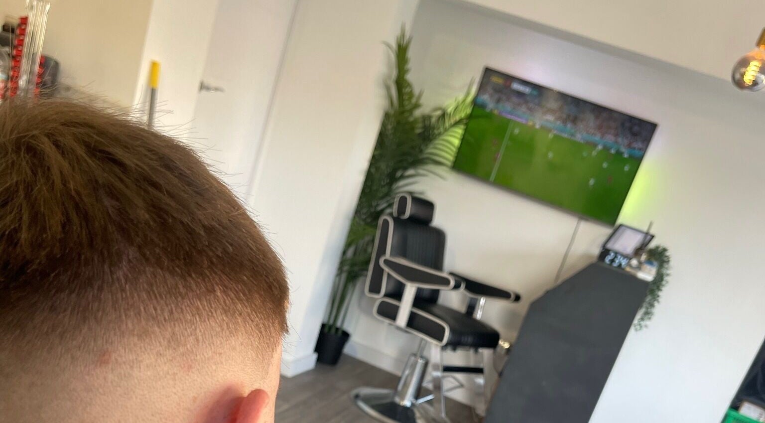 Modern barber chair and TV at John Pauls Barbershop, Lancing, England, GB.