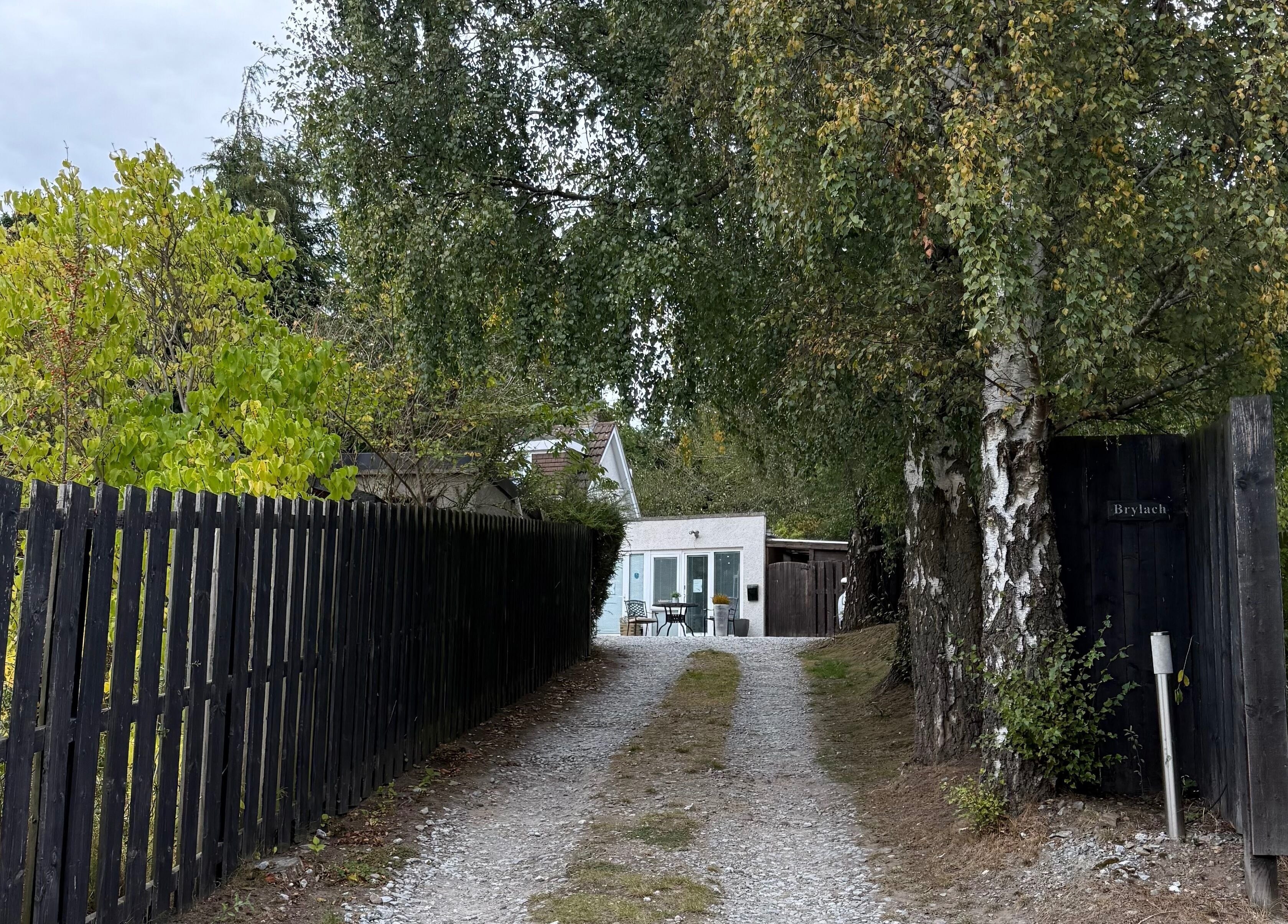Tranquil entrance to Hailey Dallas Brows, Lhanbryde, Scotland. Lush greenery frames the pathway to the venue.