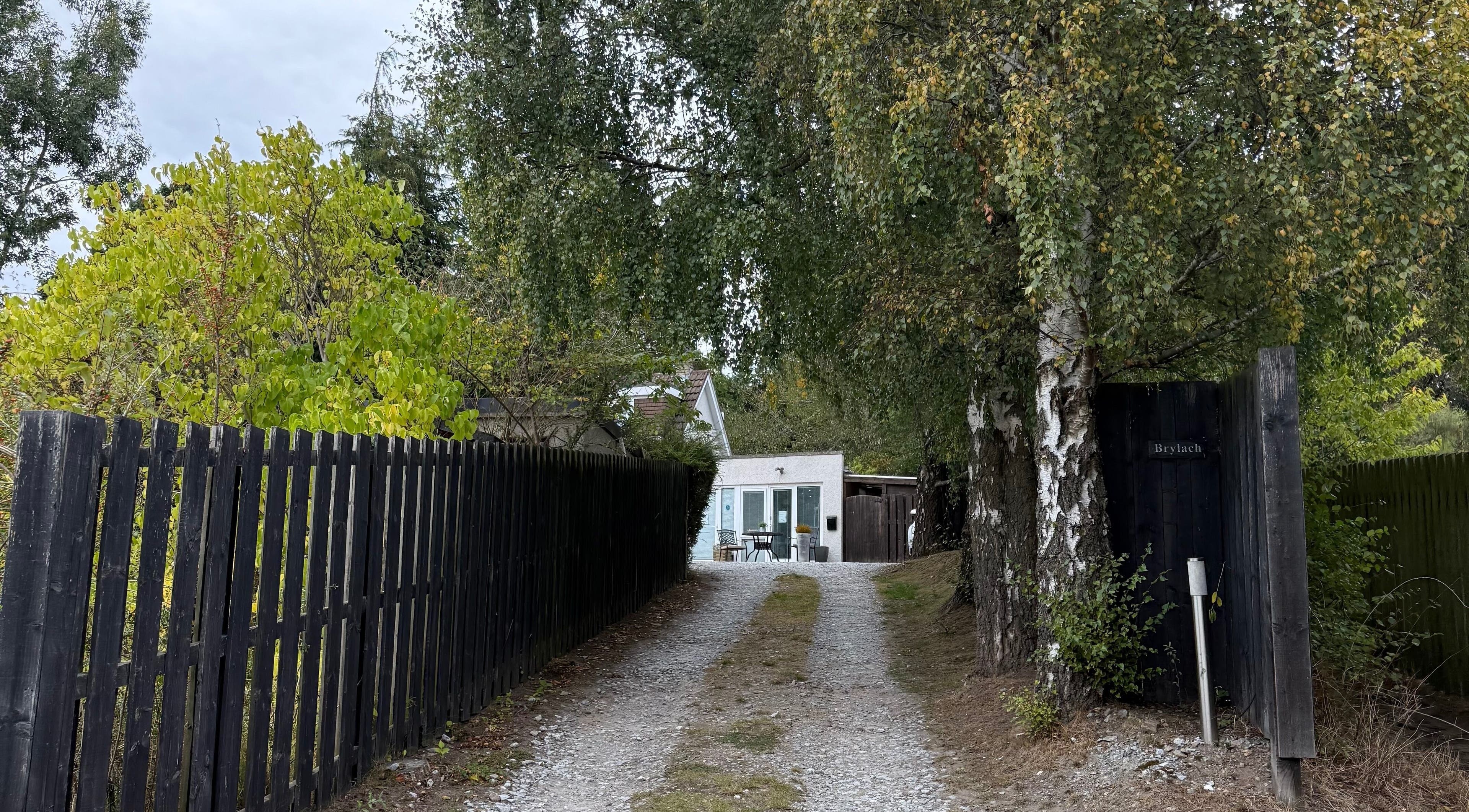 Tranquil entrance to Hailey Dallas Brows, Lhanbryde, Scotland. Lush greenery frames the pathway to the venue.