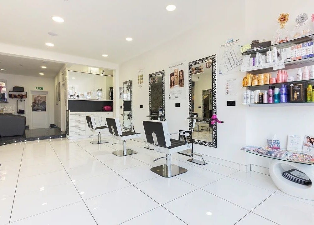Bright interior of Reflection Hair Studio in Potters Bar, England, GB showcasing sleek chairs and product shelves.