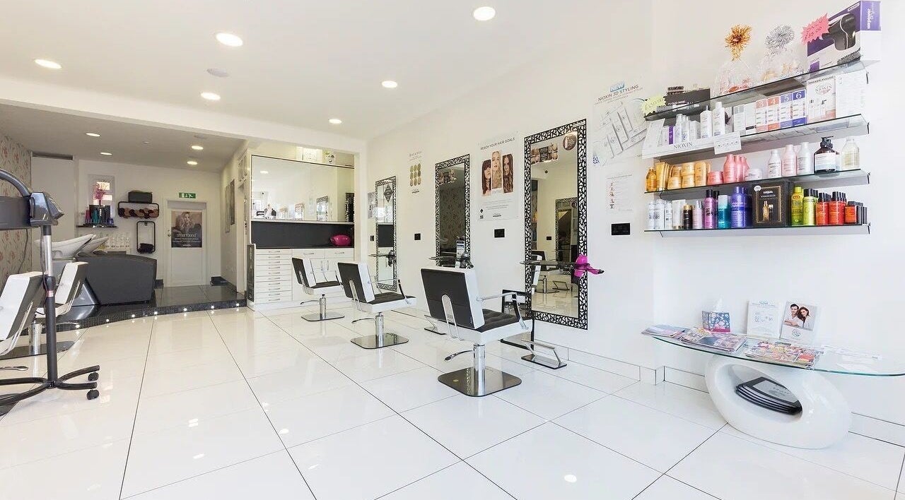 Bright interior of Reflection Hair Studio in Potters Bar, England, GB showcasing sleek chairs and product shelves.