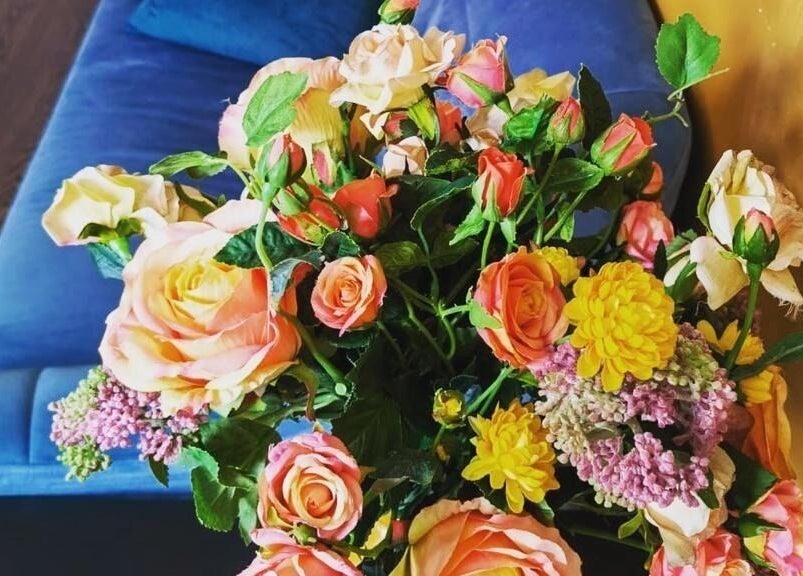 Vibrant floral arrangement on blue couch at Refresh and Spa Ltd, London, England, GB.