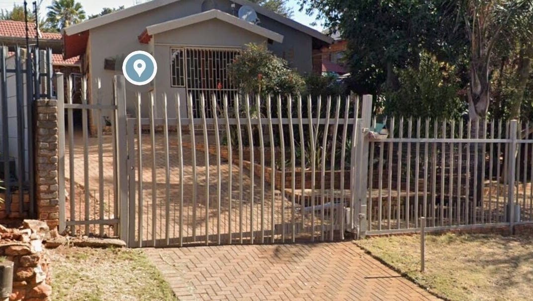 Gated entrance to The Nail Booth in Krugersdorp, Gauteng, ZA surrounded by lush greenery.