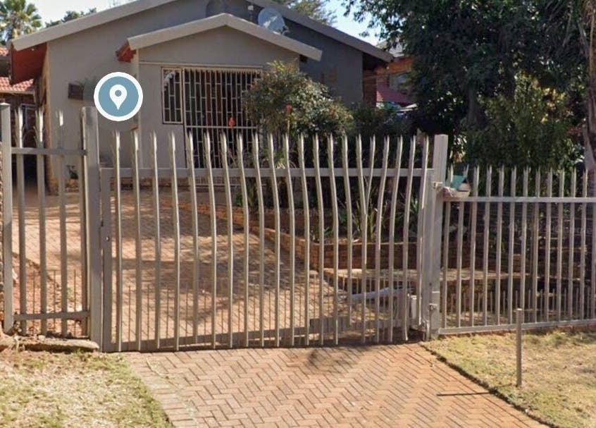Gated entrance to The Nail Booth in Krugersdorp, Gauteng, ZA surrounded by lush greenery.