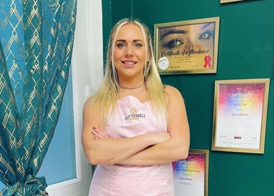 Professional at Savannah Sky Salon, Neyland, Wales, GB, showcasing certificates on a stylish green wall.