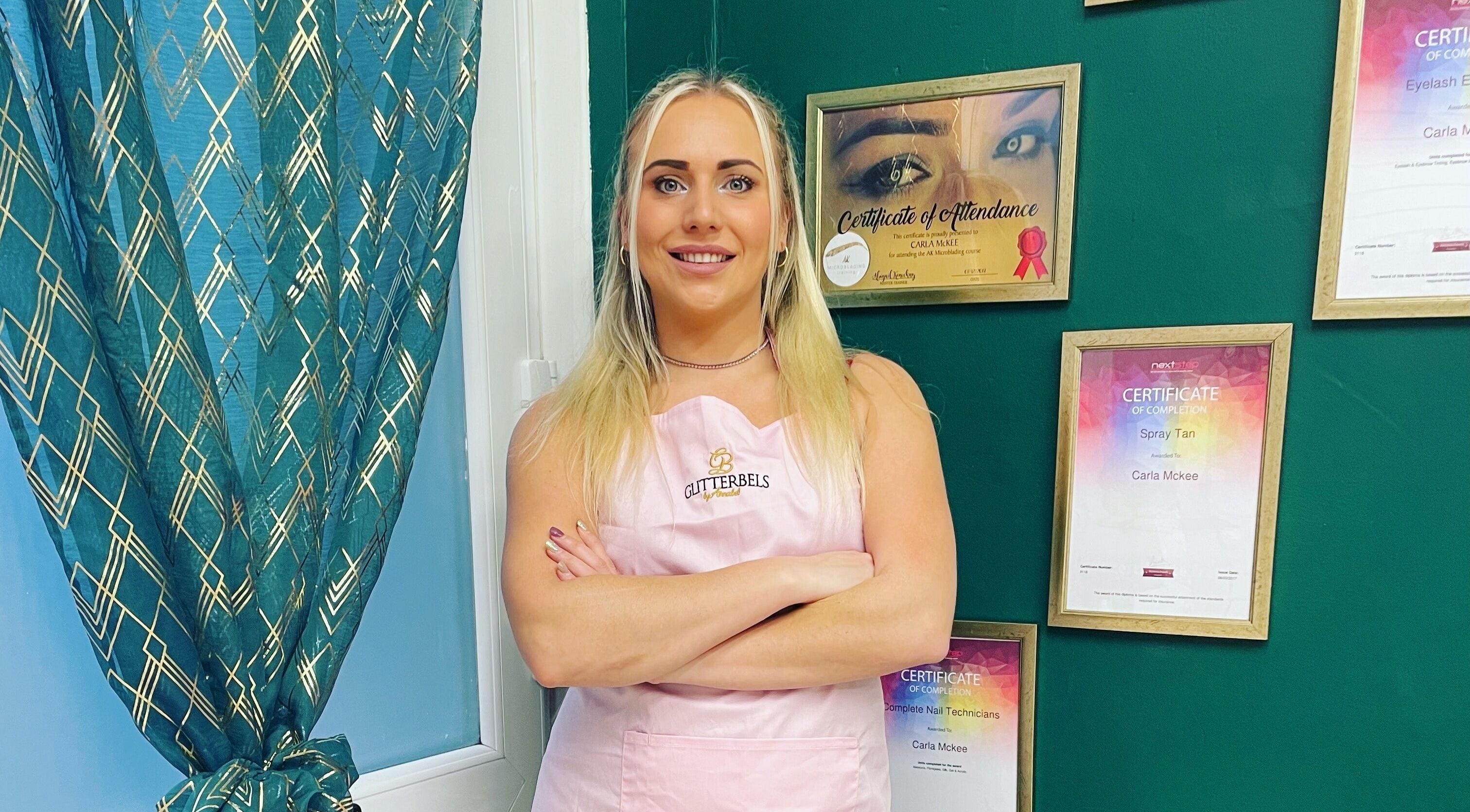 Professional at Savannah Sky Salon, Neyland, Wales, GB, showcasing certificates on a stylish green wall.