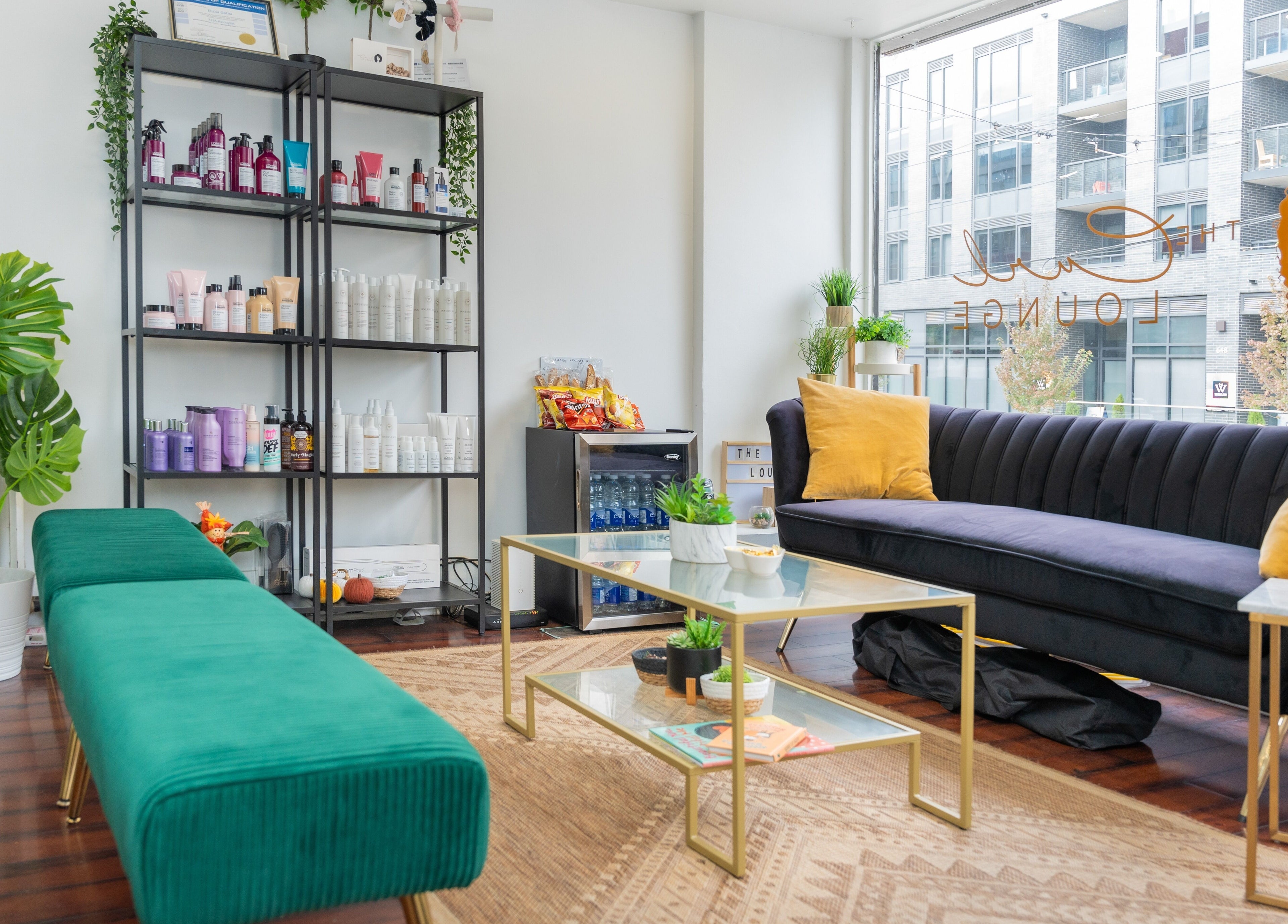 Relaxing seating at The Curl Lounge in Toronto, Ontario, CA, with vibrant decor and hair care products on display.