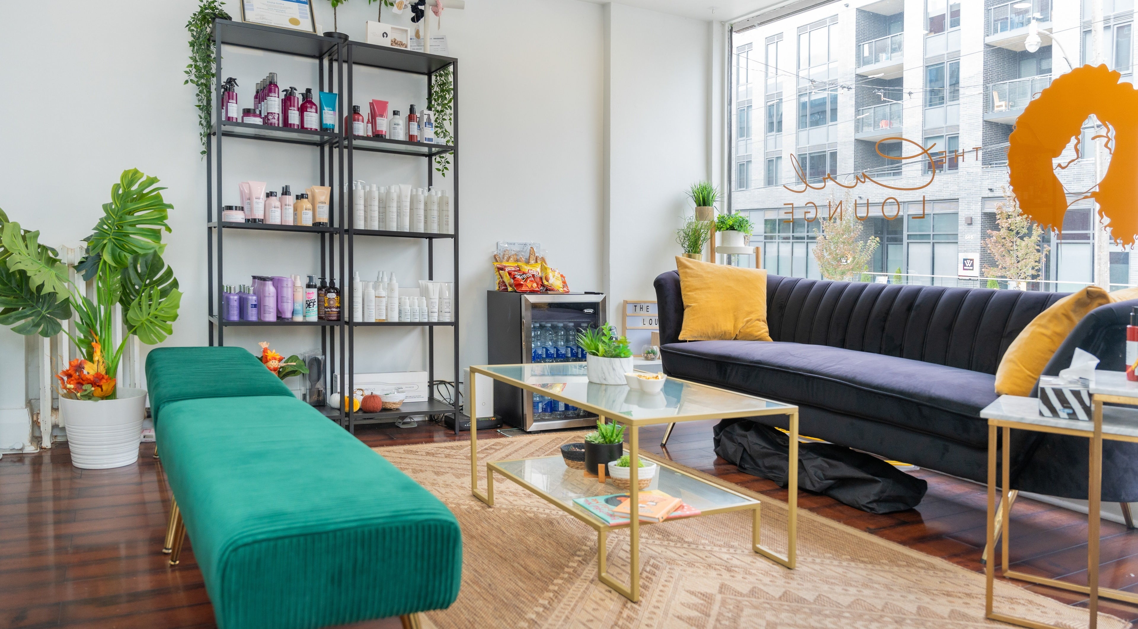 Relaxing seating at The Curl Lounge in Toronto, Ontario, CA, with vibrant decor and hair care products on display.