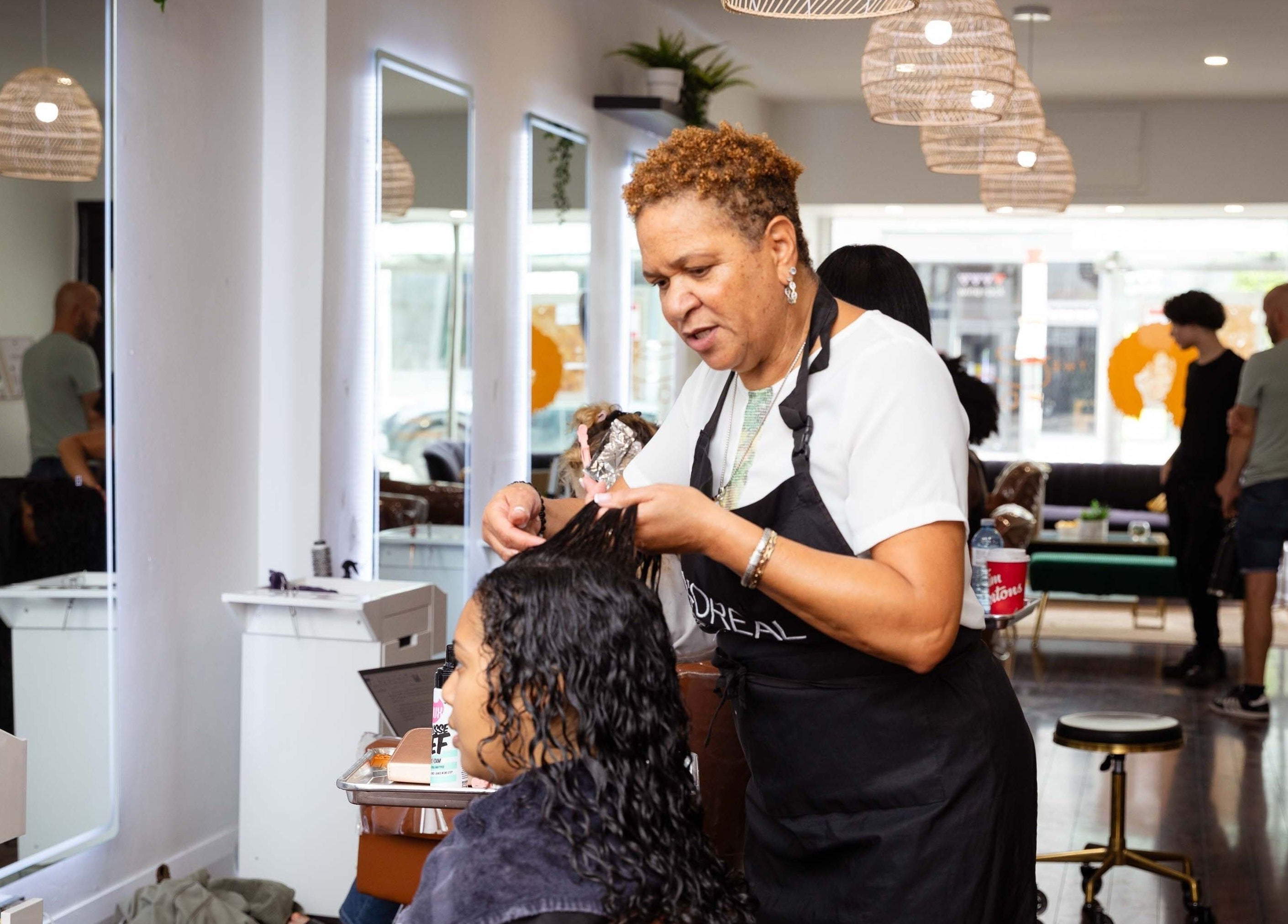Hairstylist at The Curl Lounge in Toronto, Ontario, CA working on a client's hair in a modern salon.
