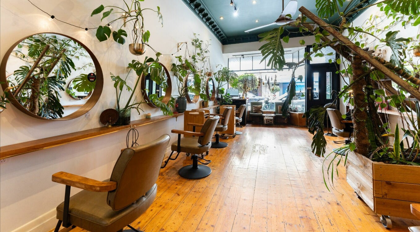 Stylish interior of Plumage Salon in Kew, Victoria, AU, featuring greenery and elegant styling stations.