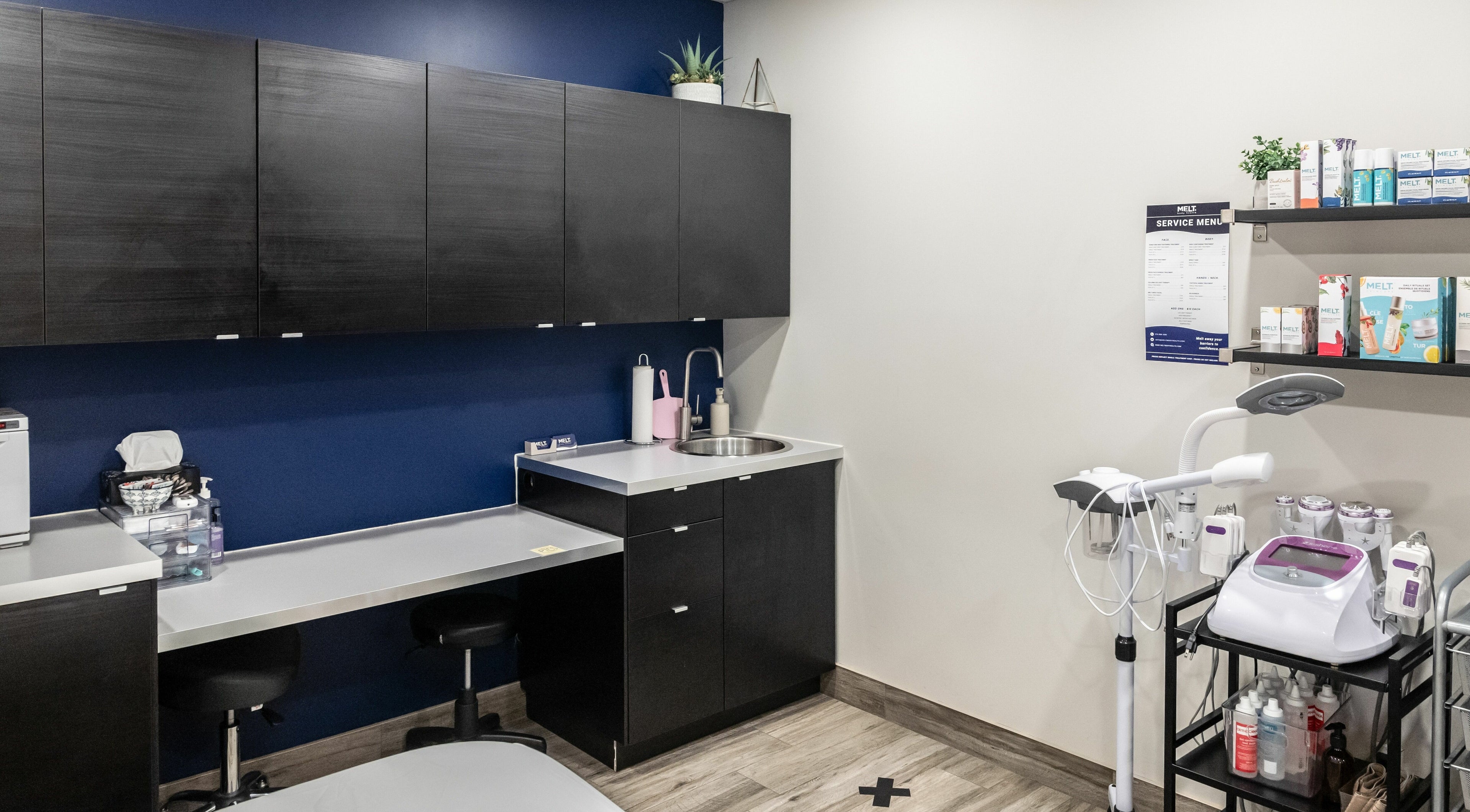 Modern treatment room at Melt Body Health, Windsor, Ontario, CA, showcasing sleek cabinetry and wellness equipment.