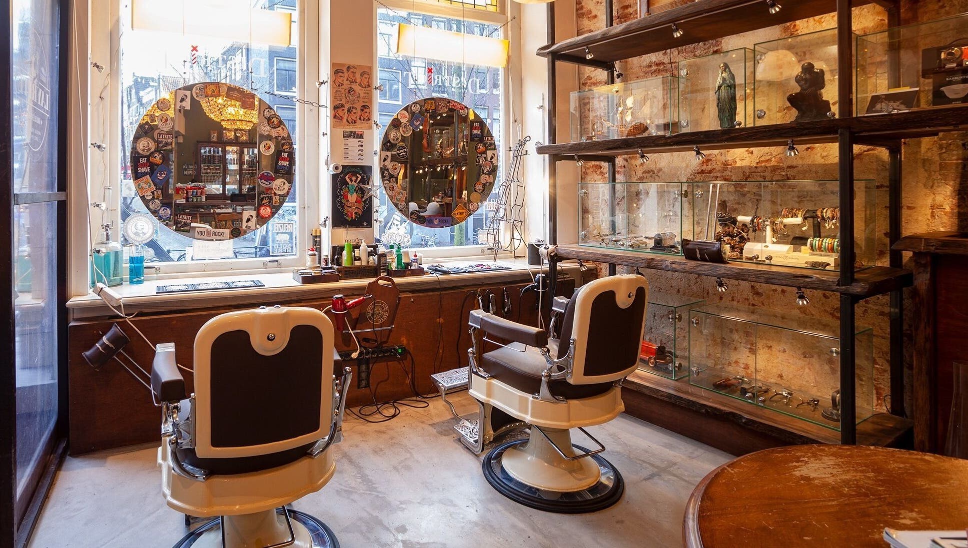 Interieur van DISTRICT BARBER in Amsterdam, Noord-Holland, NL, met vintage barbierstoelen en decoratieve rekken.