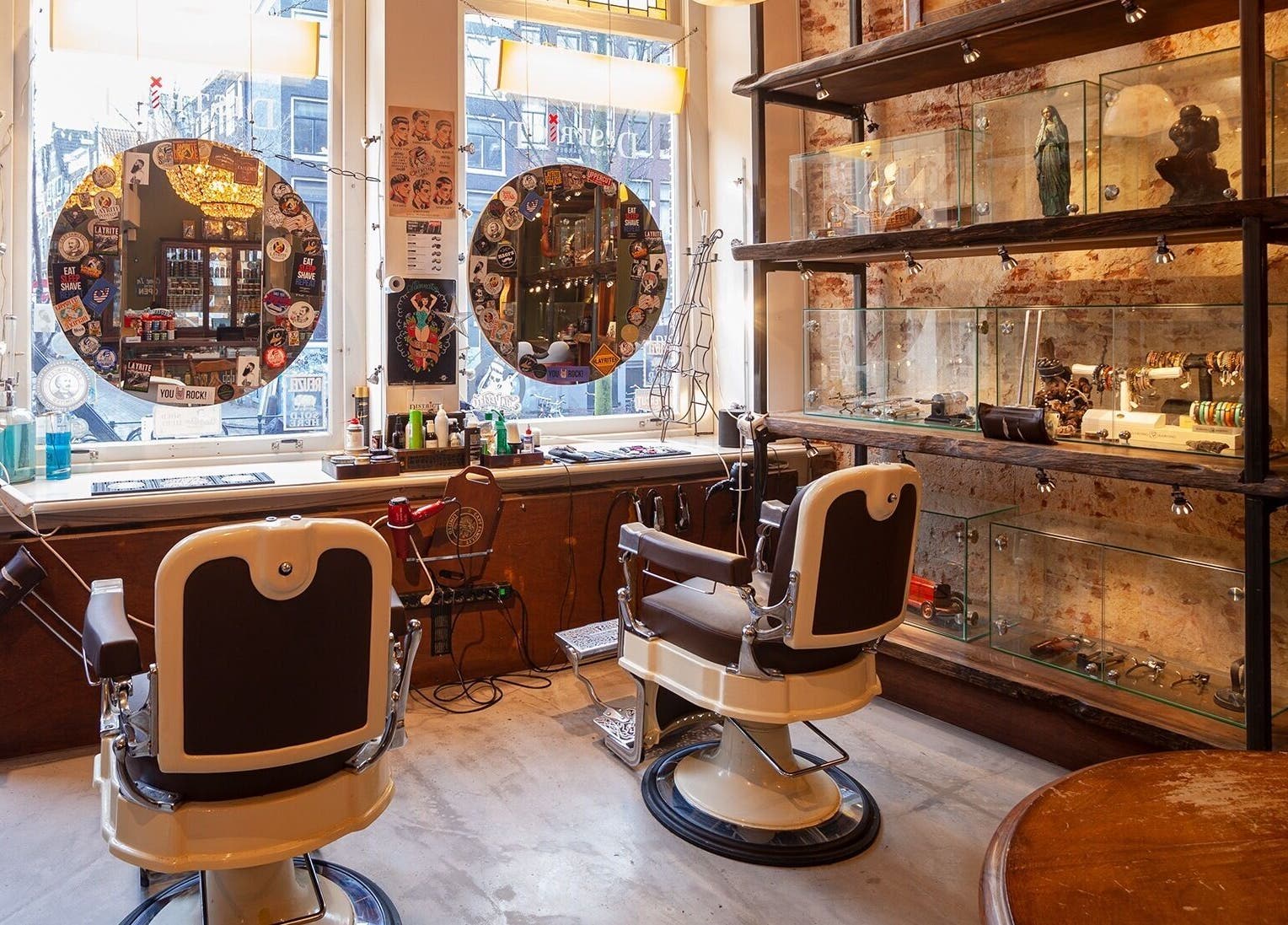Interieur van DISTRICT BARBER in Amsterdam, Noord-Holland, NL, met vintage barbierstoelen en decoratieve rekken.