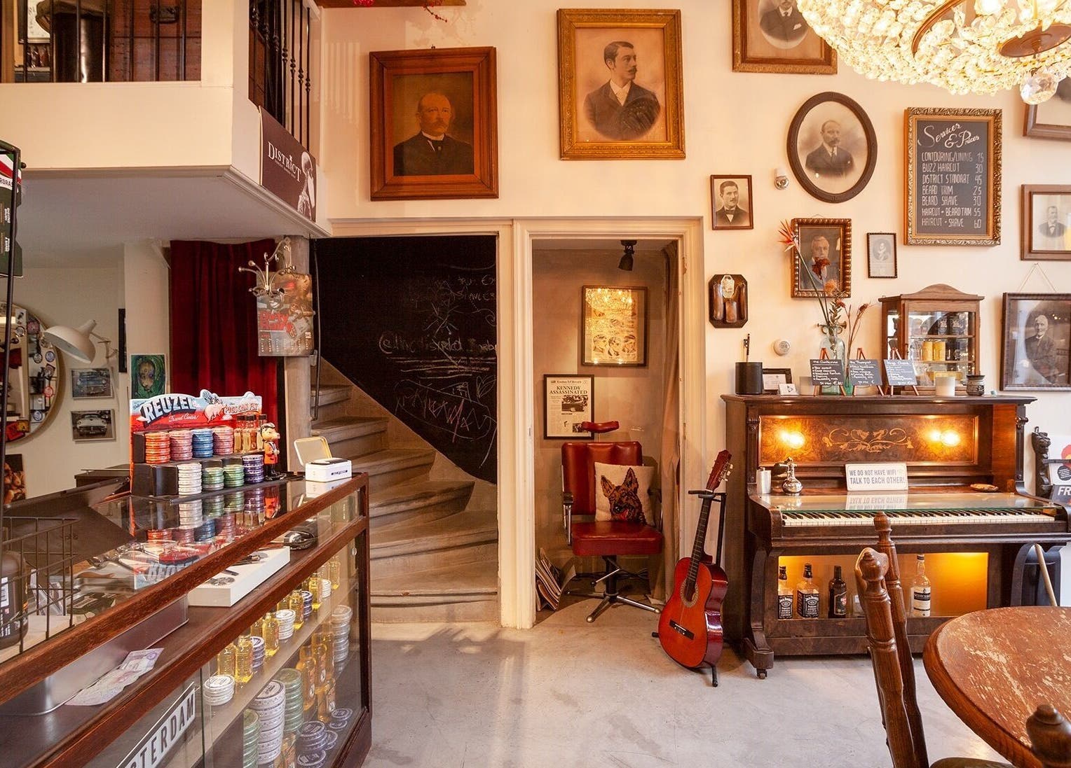 Interieur van DISTRICT BARBER in Amsterdam, Noord-Holland, NL met vintage decor en een klassieke piano.