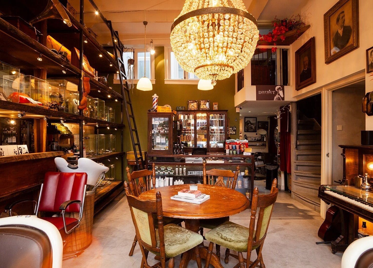 Stijlvol interieur van DISTRICT BARBER, Amsterdam, met een kroonluchter en antiek meubilair.