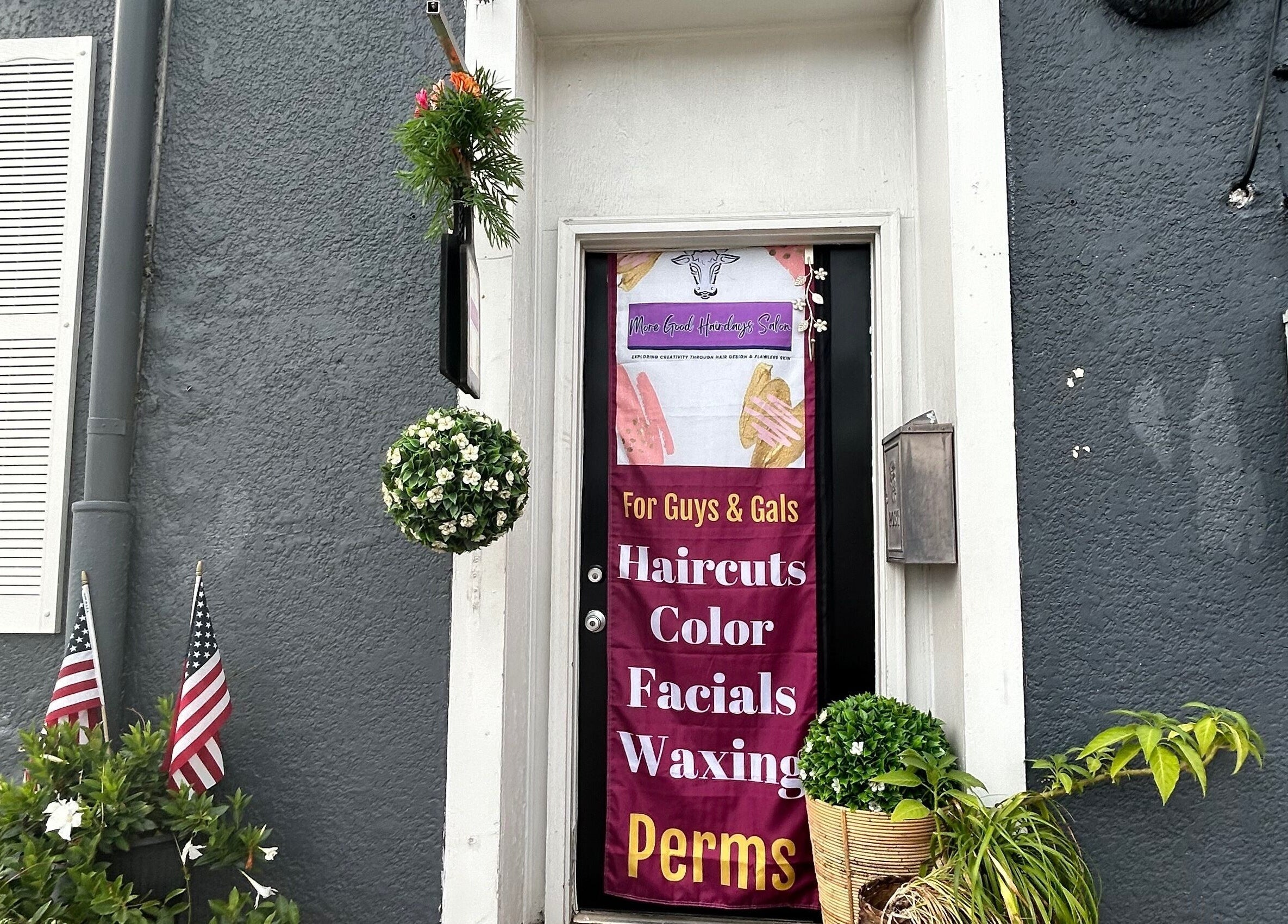 Entrance of More Good Hair Days Salon in Forsyth, Georgia, US with vibrant sign and potted plants.