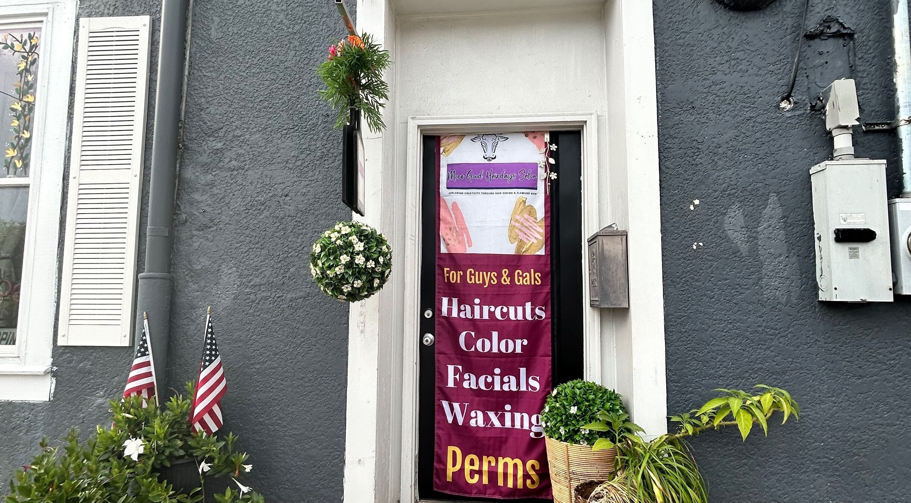Entrance of More Good Hair Days Salon in Forsyth, Georgia, US with vibrant sign and potted plants.