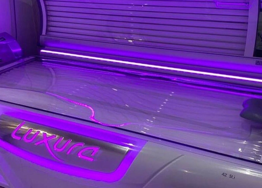 Luxura tanning bed at Beautiful Bodies & Aesthetics, Bournemouth, England, GB. Sleek design, vibrant purple lighting.