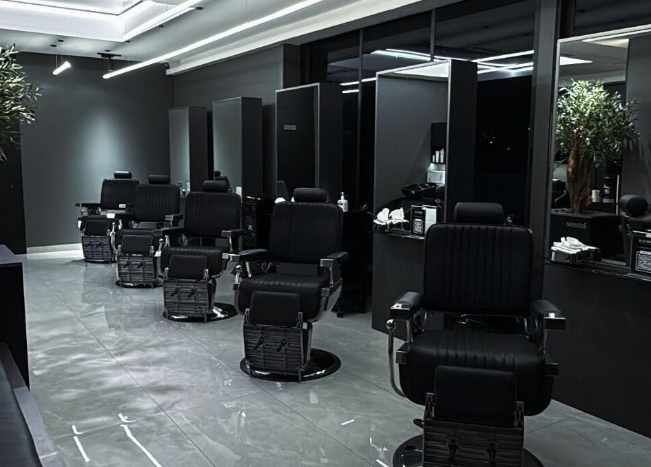 Modern barber shop interior at Barber, Amman, Amman Governorate, JO, featuring stylish black chairs and mirrors.