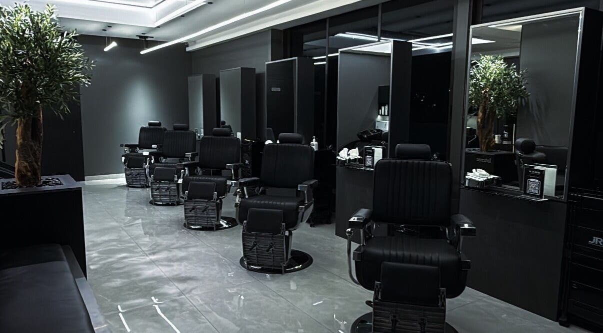 Modern barber shop interior at Barber, Amman, Amman Governorate, JO, featuring stylish black chairs and mirrors.