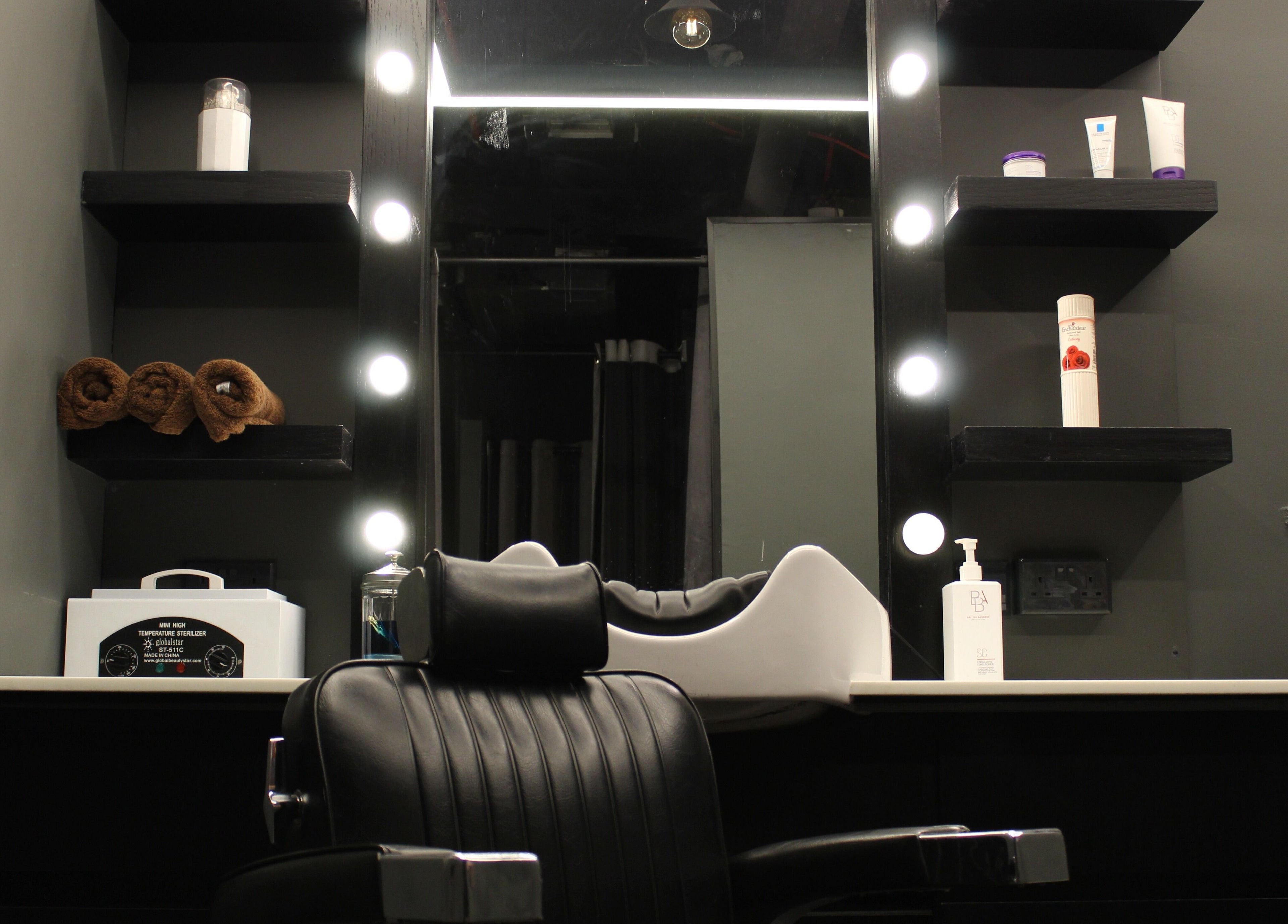 Stylish barbershop station at Musk Barbershop JVC, Dubai, Dubai, AE, featuring a lit mirror and grooming tools.