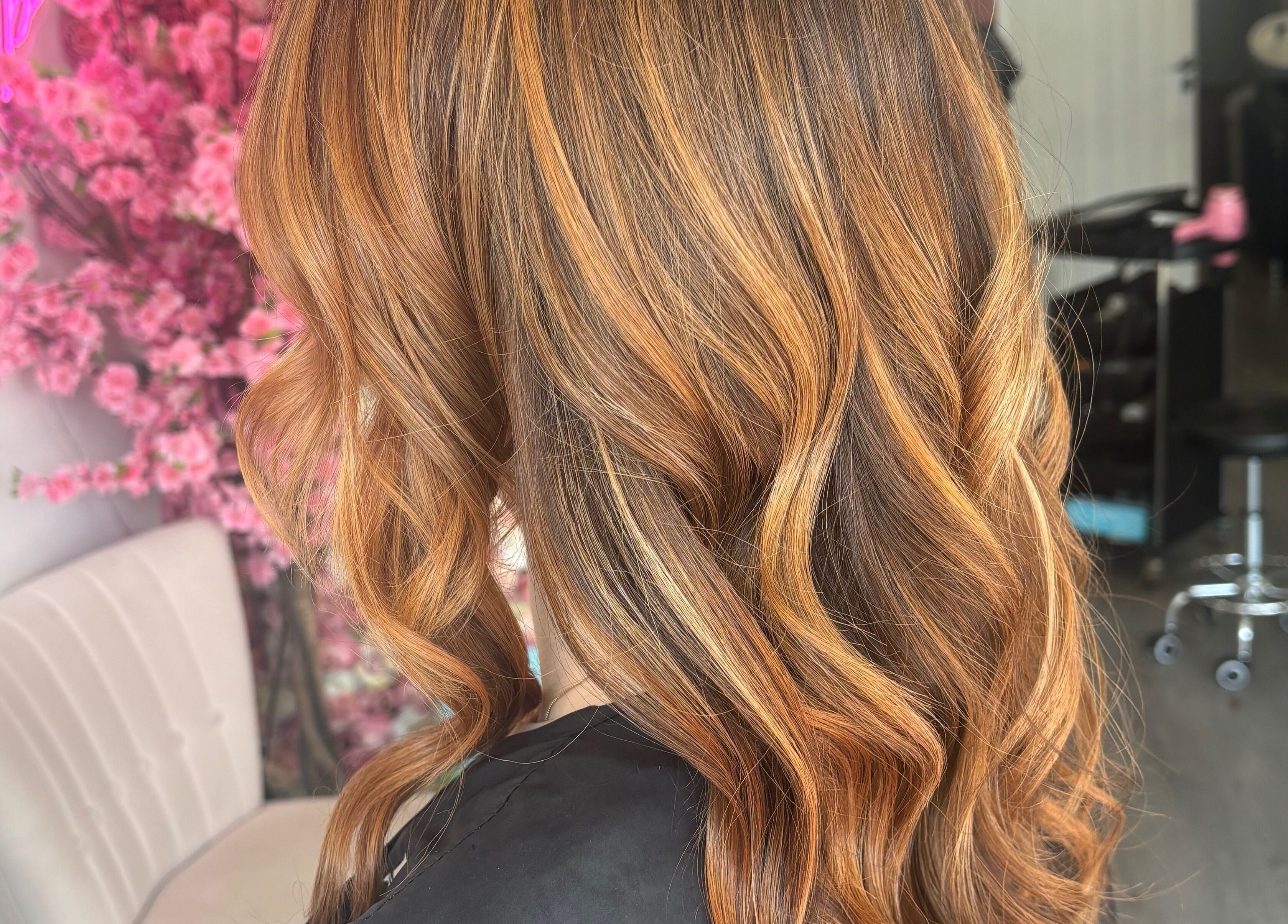 Elegant wavy hairstyle at Emily Sinclair Hair, Congleton, England, GB salon with pink floral decor.