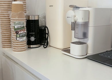 Coffee station at Lash by Daria, London, England, GB, featuring eco-friendly cups and a sleek machine.