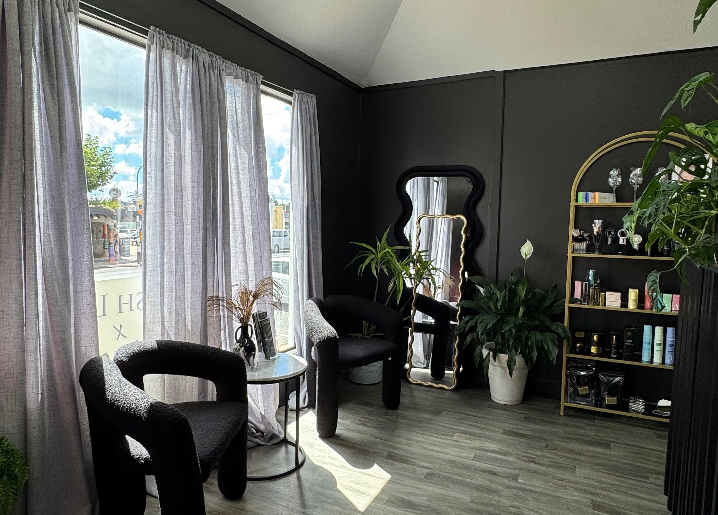 Elegant lounge area at StudioEDIT in Kawakawa, Northland, NZ with black chairs and green plants.