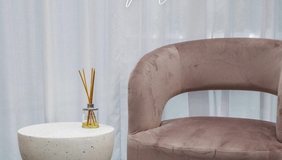 Elegant seating at Lux Hair Lounge, Narellan, New South Wales, AU with soft pink chair and diffuser on a table.