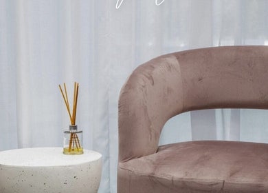 Elegant seating at Lux Hair Lounge, Narellan, New South Wales, AU with soft pink chair and diffuser on a table.