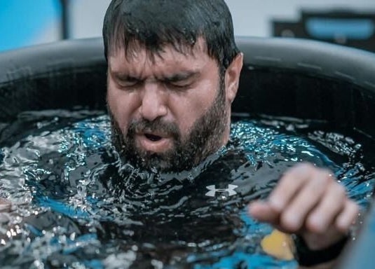 Man in ice bath at Celsius Cold Water Immersion, Abu Dhabi, AE, experiencing rejuvenation.