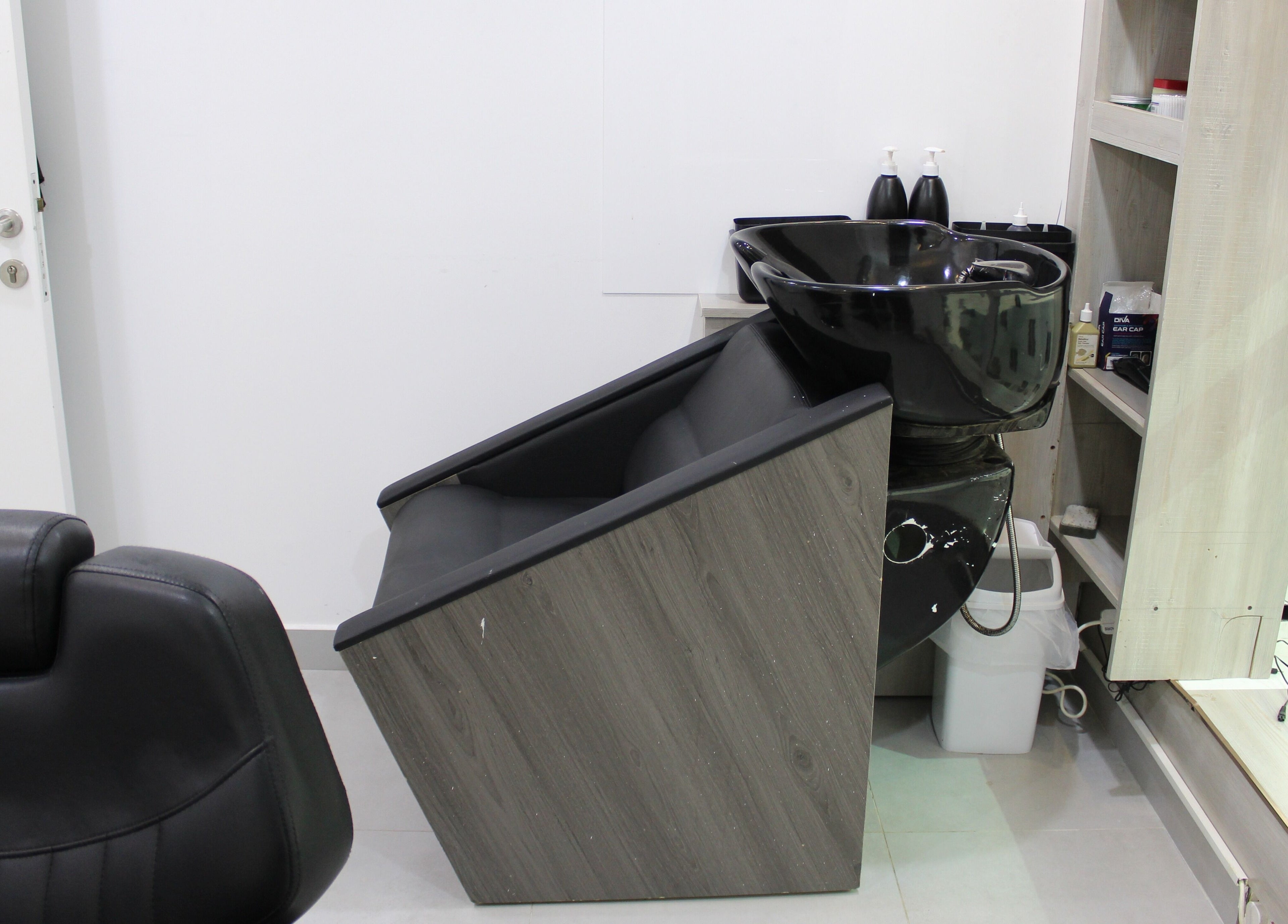 Modern salon washstation at New Images, Dubai, 127825, AE. Comfortable chair with black basin.