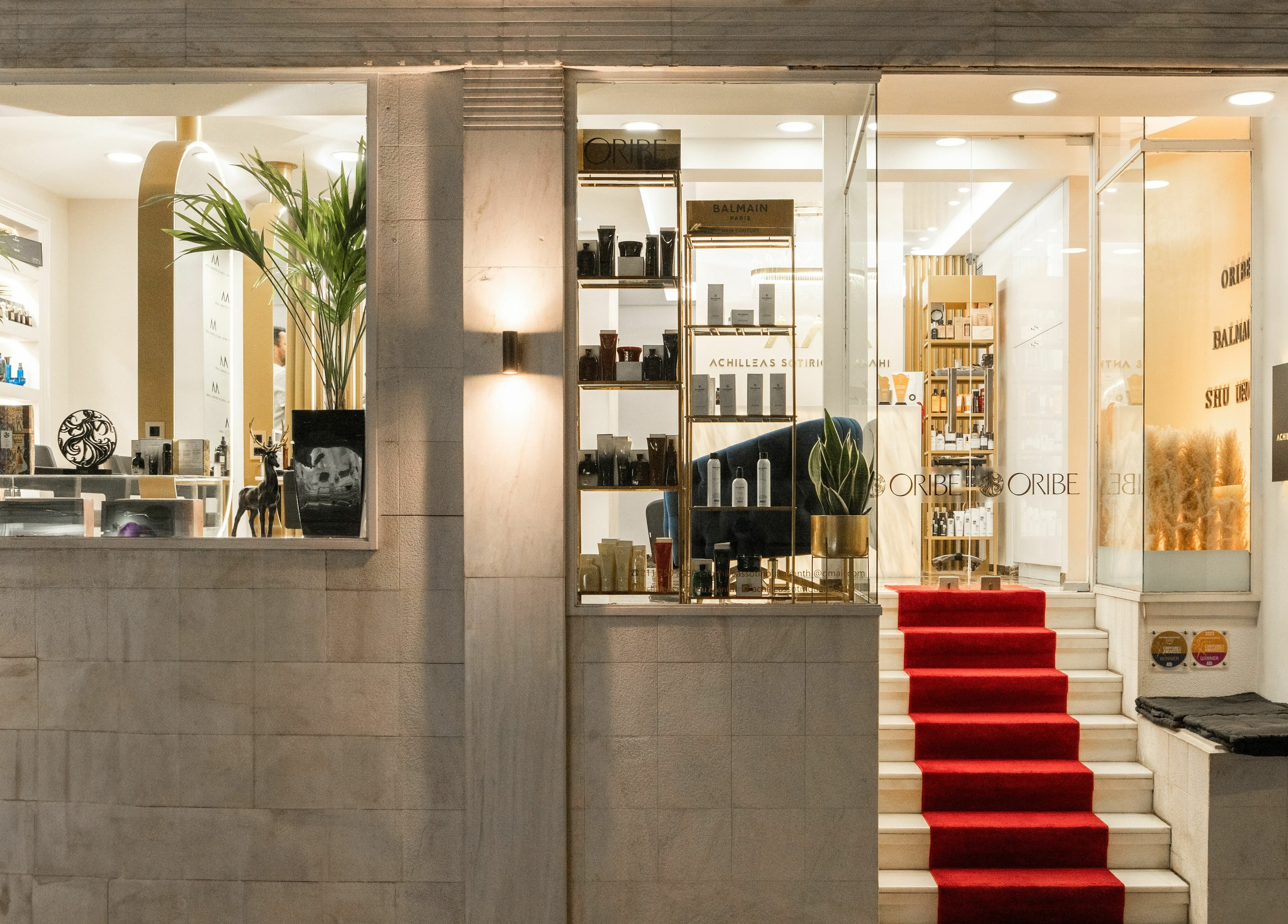 Κομψή είσοδος ACHILLEAS SOTIRIOY & ANTHI στην Αθήνα, GR με κόκκινο χαλί και βιτρίνες προϊόντων.