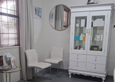 JustBe Aesthetics Skin Clinic waiting area with white cabinet, chairs, and decor in Cape Town, Western Cape, ZA.