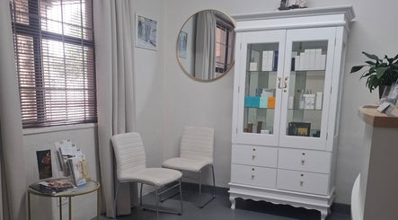 JustBe Aesthetics Skin Clinic waiting area with white cabinet, chairs, and decor in Cape Town, Western Cape, ZA.