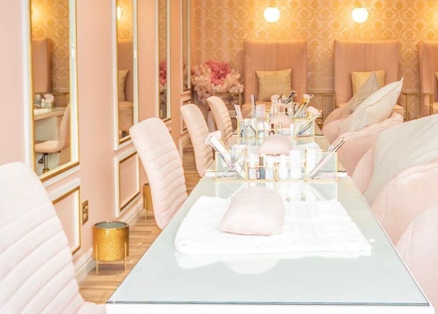 Chic interior of Rose Blvd Beauty Bar SEA POINT, Cape Town, Western Cape, ZA with soft pink seating and lights.