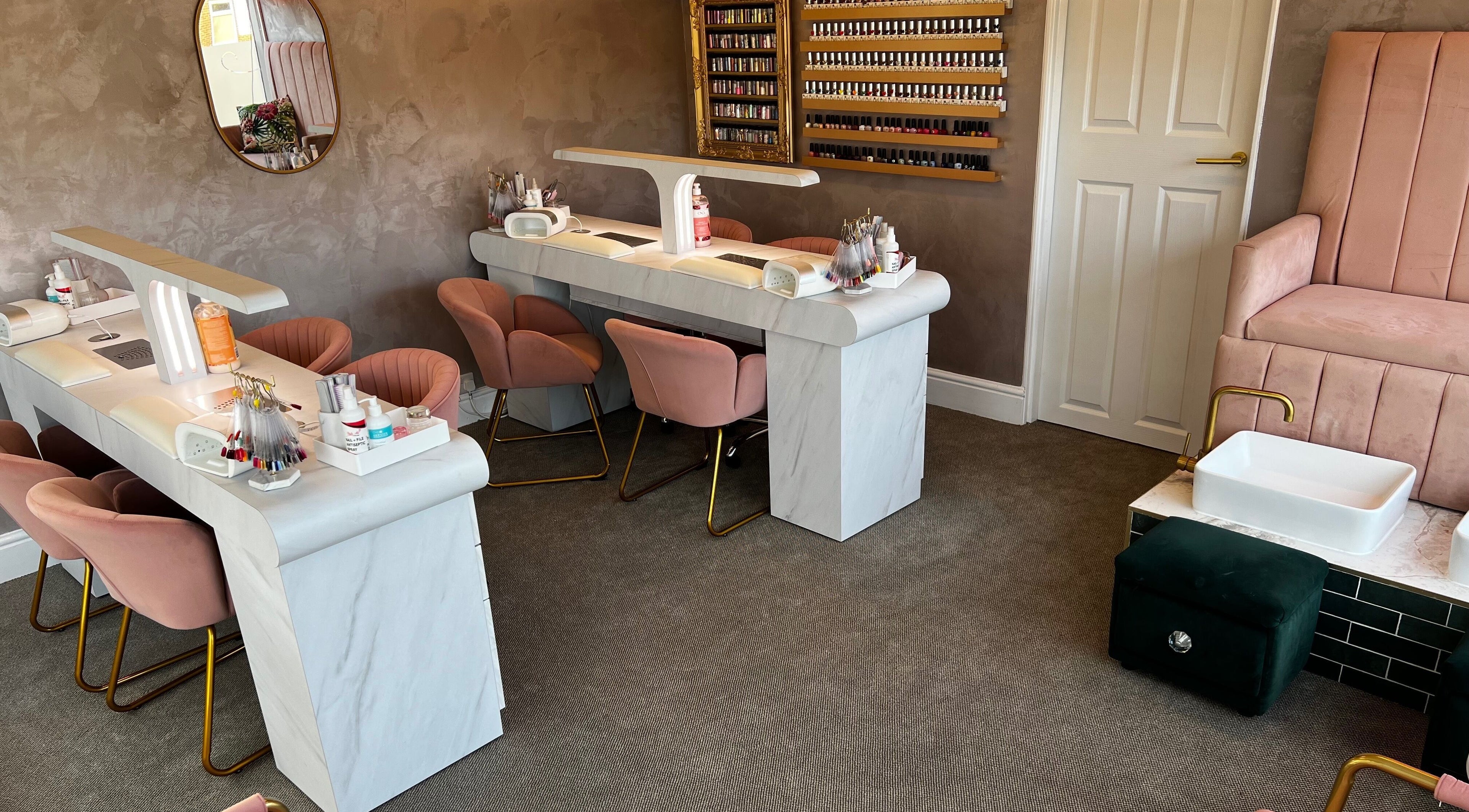 Elegant nail salon setup at Nails by Beau Monde, Derby, England, GB, featuring plush pink chairs and manicure stations.