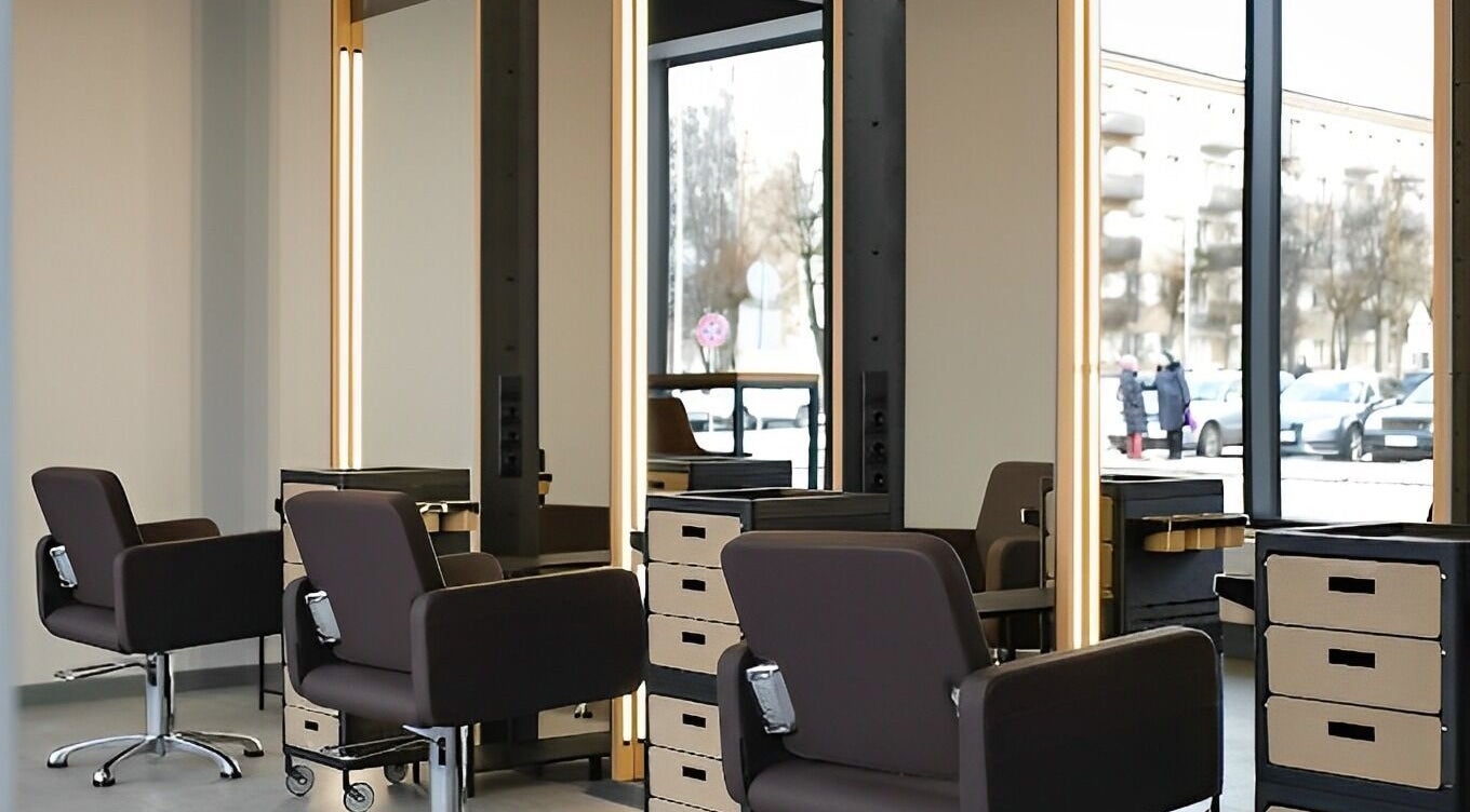 Modern salon stations at Skaistuma ēra in Jelgava, LV, featuring sleek chairs and mirrors for a luxurious experience.