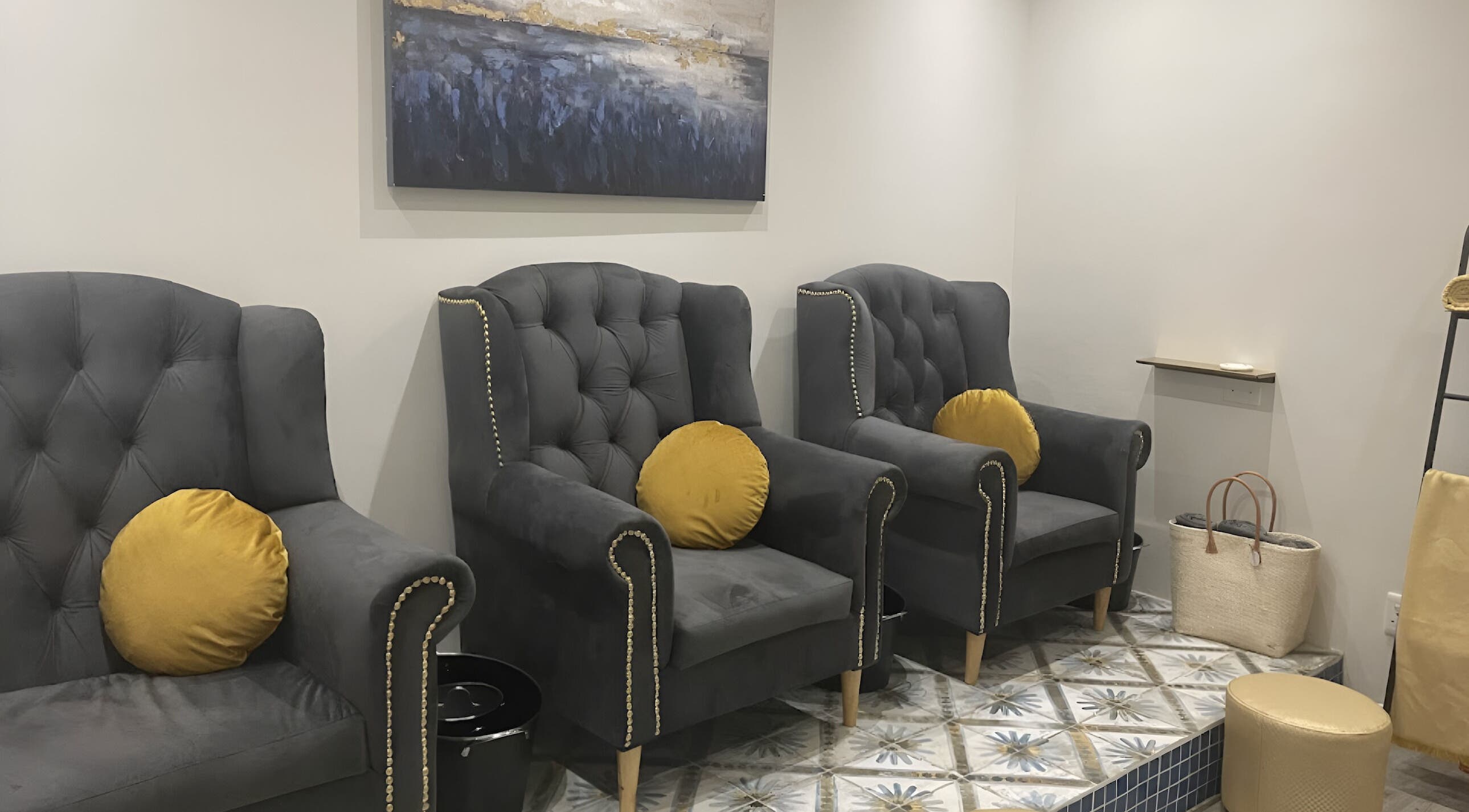 Luxurious seating area at Sana Salon in Cape Town, Western Cape, ZA, featuring plush grey chairs and art.