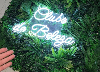 Неоновая вывеска Клиник Clube de Beleza - Cabeleireiro Estética, окруженная зеленью в Амадоре, Лиссабон, Португалия.
