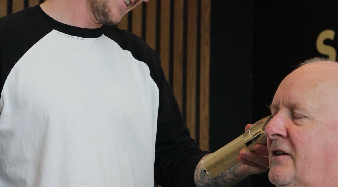 A barber trims a man's hair at Section Yas Bay, Abu Dhabi, AE, enhancing his grooming experience.