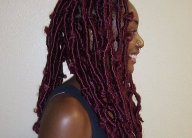 Side view of vibrant red locs styled at Isl Hair Care in Lawrence, Kansas, US.