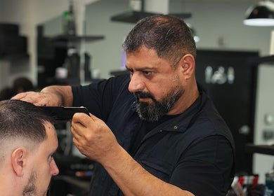 Barber styling client hair at Yonan's Barber Shop, Hamilton, Ontario, CA, showcasing expert grooming skills.