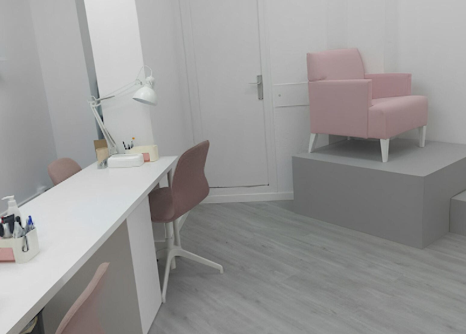 Área elegante de Helen Nails en Barcelona, Catalunya, ES con sillas rosas y mesa blanca.