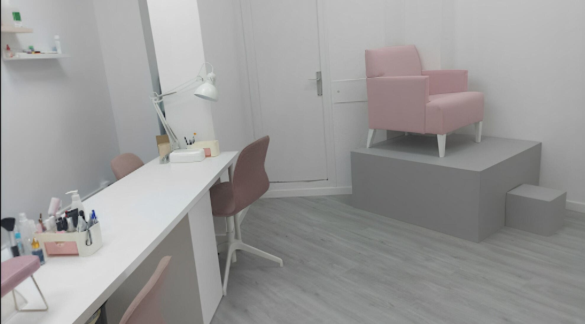 Área elegante de Helen Nails en Barcelona, Catalunya, ES con sillas rosas y mesa blanca.