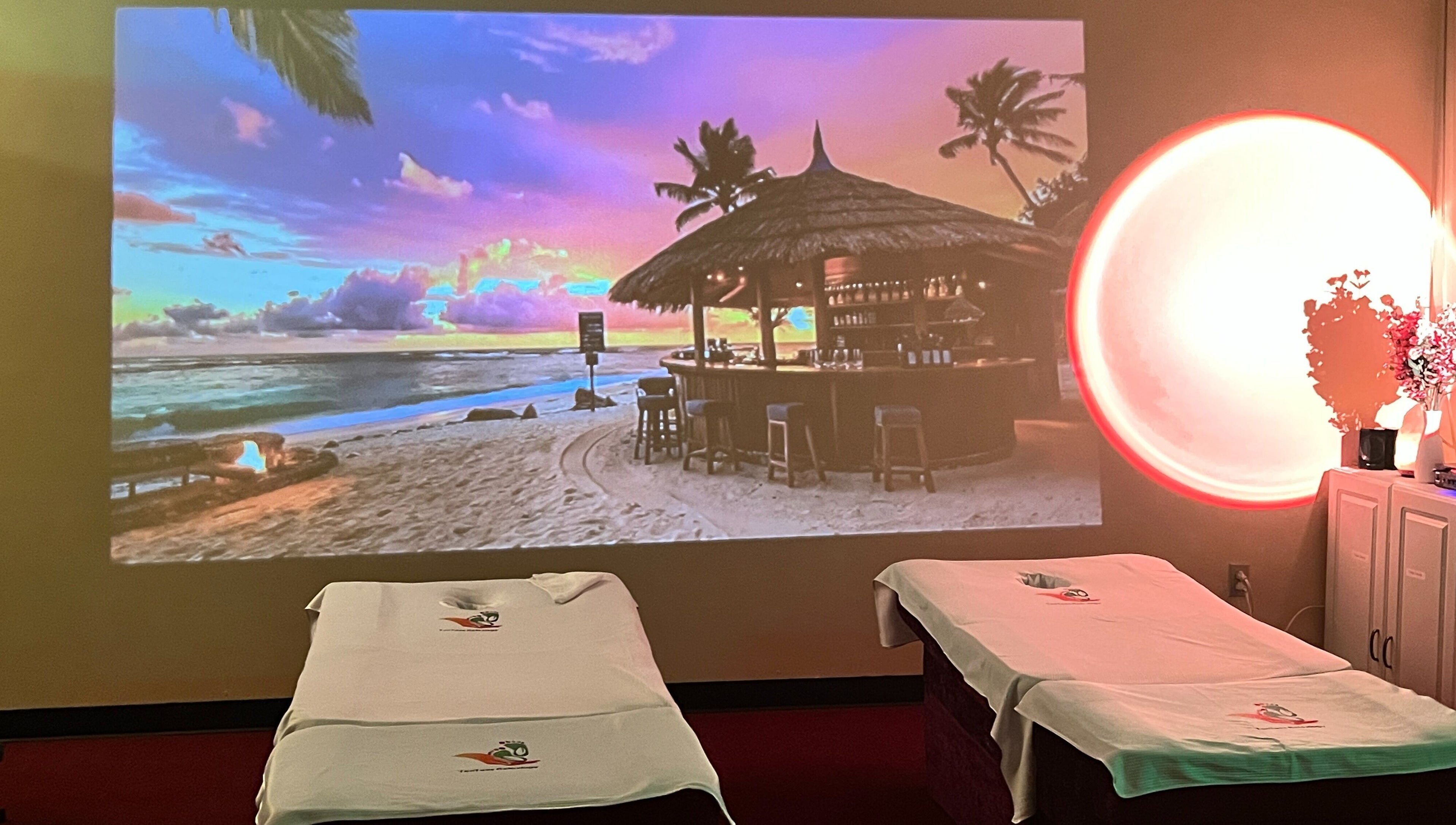 Relaxing massage beds at Ten Toes Reflexology, Lawrence, Kansas, US, with beach sunset projection.