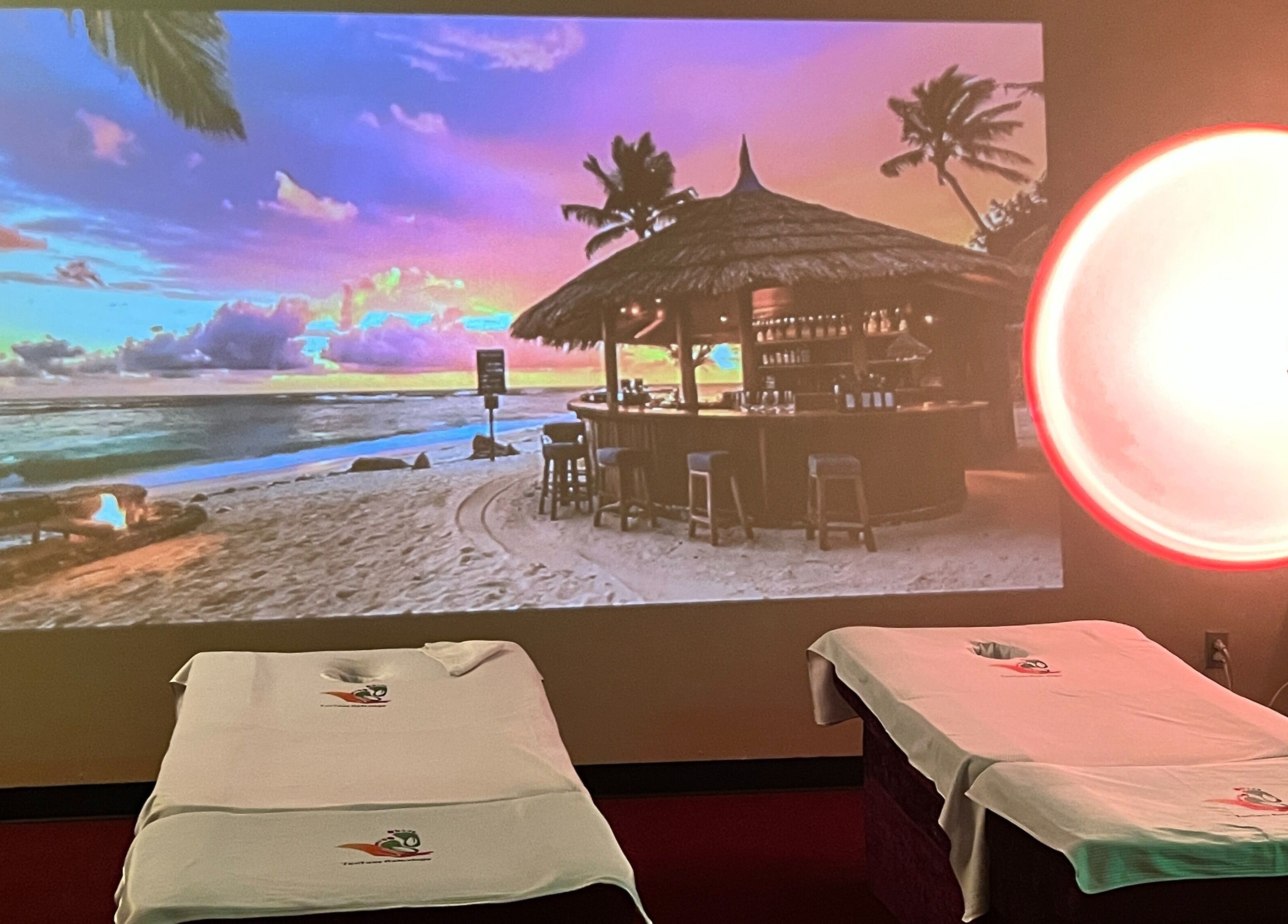Relaxing massage beds at Ten Toes Reflexology, Lawrence, Kansas, US, with beach sunset projection.